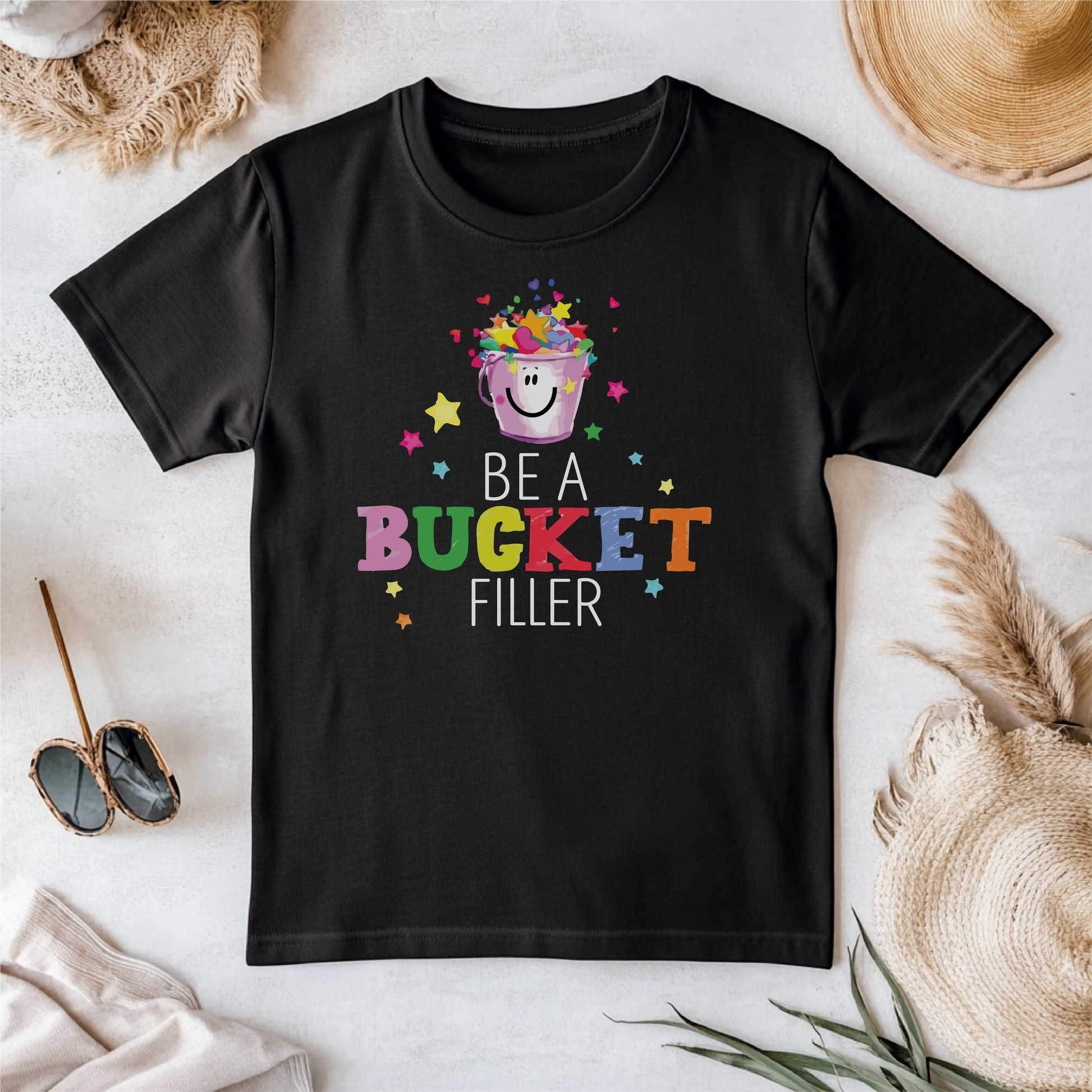 Bucket Filler T-shirt featuring a cheerful bucket filled with hearts and stars, surrounded by colorful text encouraging positivity and kindness.