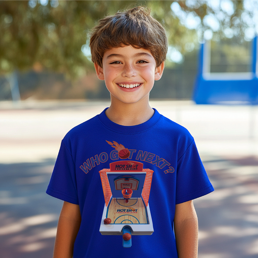 Who Got Next? retro basketball arcade graphic on a royal blue youth t-shirt, modeled by a smiling child outdoors at a basketball court.